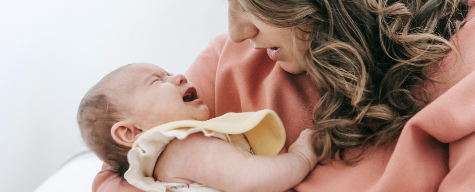 A mother cradles and attempts to soothe her crying baby