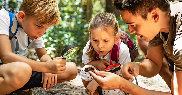 father and kids examining pinecone