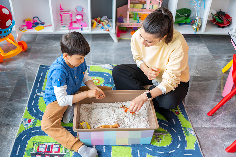 child and therapist working in sandbox