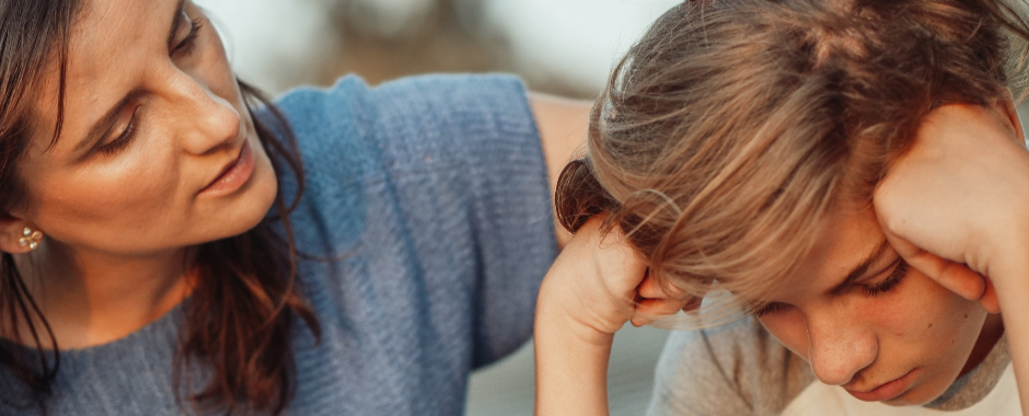 ADHD signs symptoms Knowledge Base Sized header (940 x 380px) A mother comforts her teen son who is looking down with hands pressed to head