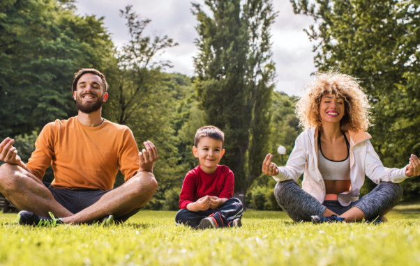 A family with young son sit in yoga poses smiling