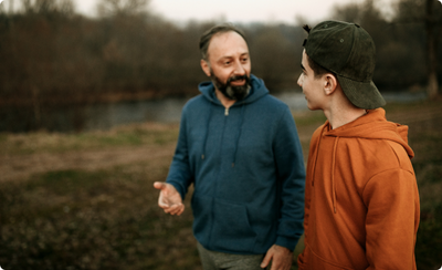 A father talking with his teenage son on a walk in a forest