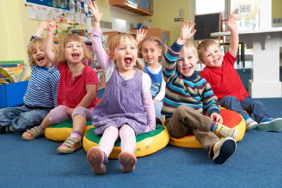Smiling group of Transitional Kindergarten children raising hands